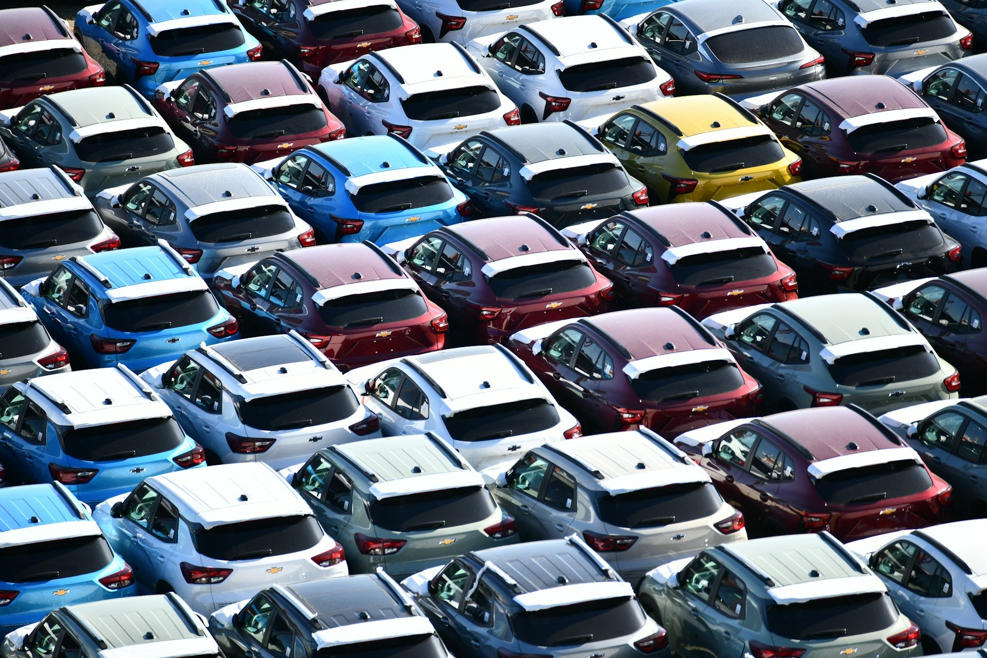 Rows of new cars parked in a large lot 
